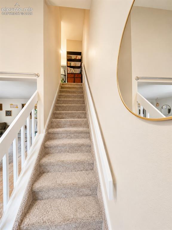 Image 13 of 27: Carpeted staircase with white railings and painted walls