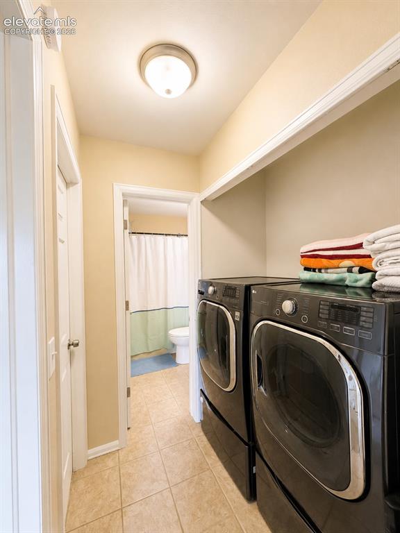 Image 15 of 27: Laundry area featuring light-toned tile flooring, built-in shelving, and a 