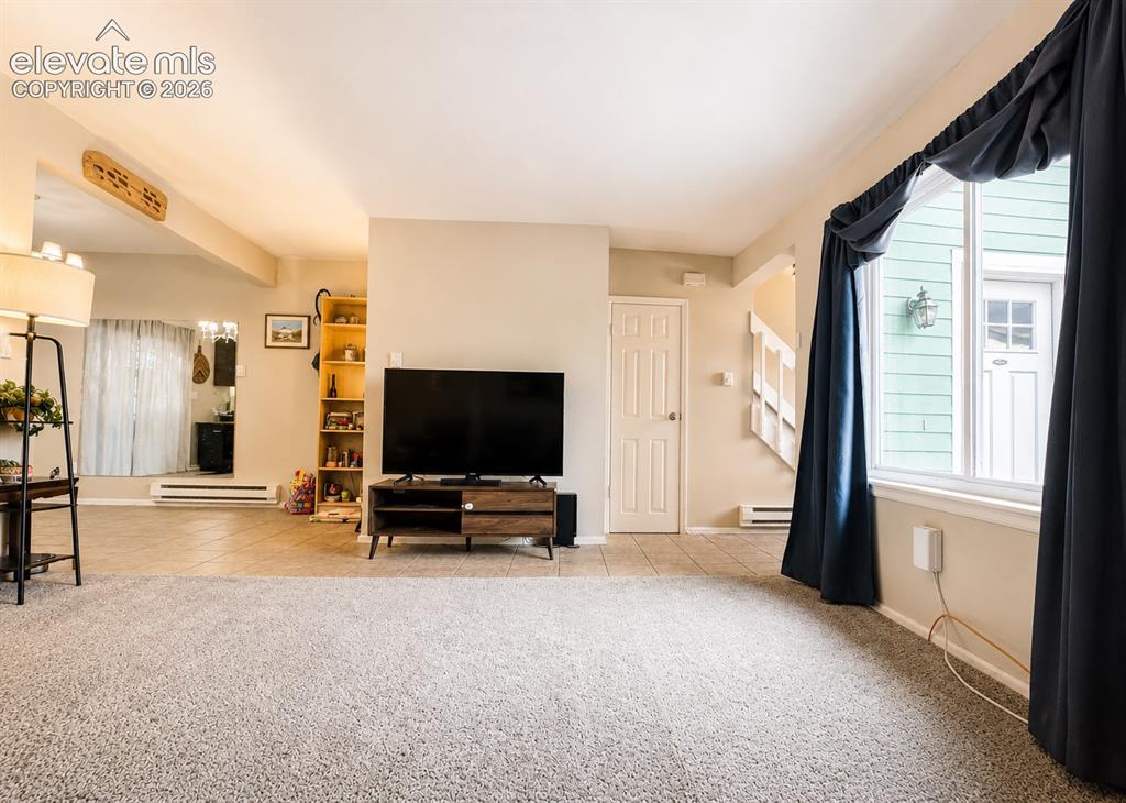 Image 2 of 27: Spacious living area featuring light-colored walls and plush carpeting