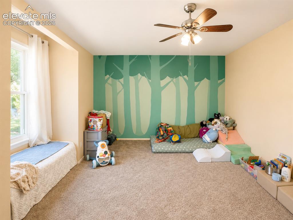 Image 21 of 27: Carpeted room featuring a window with a built-in bench, a ceiling fan with 