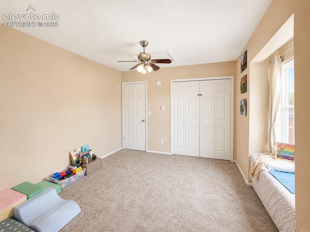 Image 22 of 27: Carpeted room featuring a ceiling fan, two white bi-fold closet doors, and 