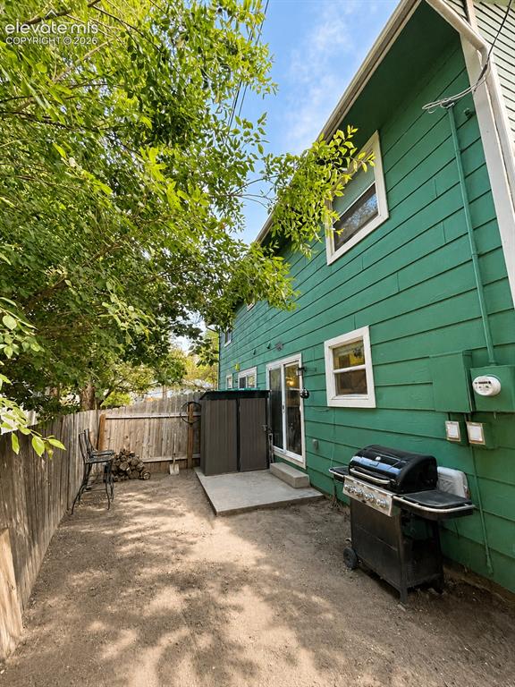 Image 23 of 27: Rear exterior featuring green horizontal siding and white trim