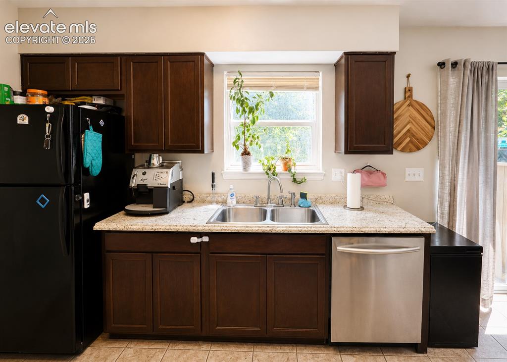 Image 5 of 27: Kitchen featuring dark wood cabinetry, light speckled countertops, and a do
