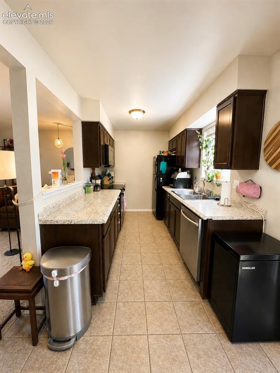 Image 6 of 27: Galley kitchen featuring dark wood-finish cabinetry, light-toned speckled c