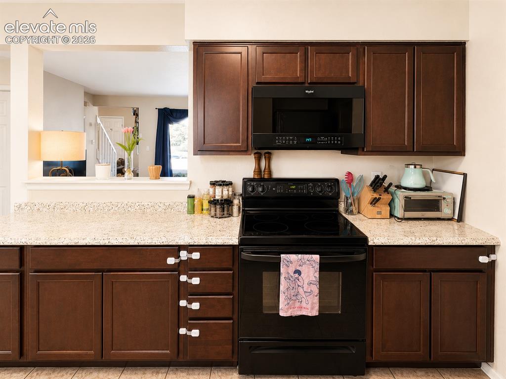 Image 8 of 27: Kitchen featuring rich wood-finish cabinetry, light-toned countertops, and 