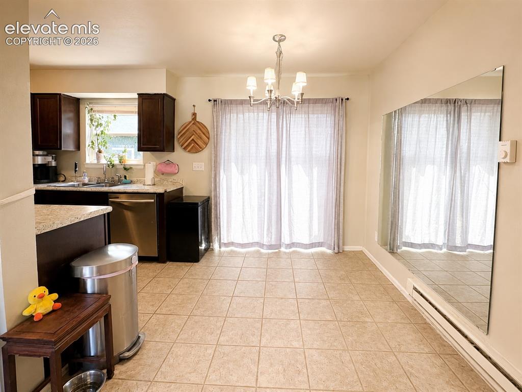 Image 9 of 27: Kitchen and dining area featuring dark wood cabinetry, light granite-style 