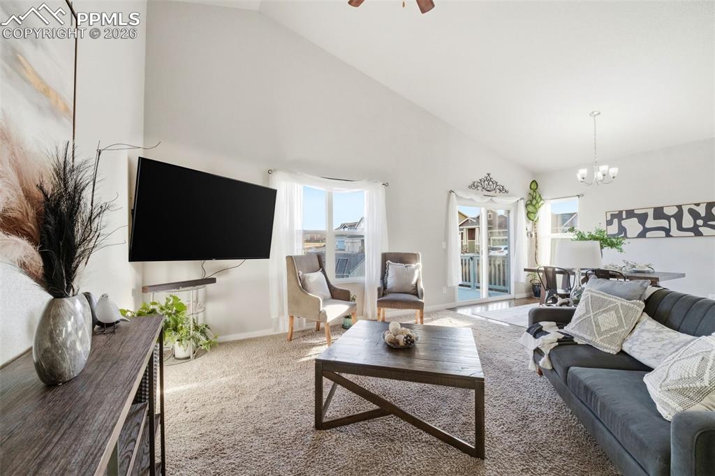 Image 29 of 50: Carpeted living area with lofted ceiling, a ceiling fan, and hanging lights