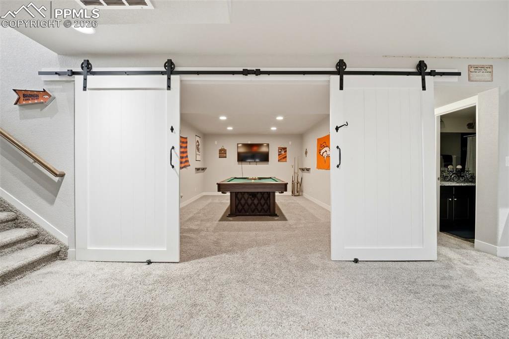 Image 31 of 50: Playroom featuring a barn door, light colored carpet, recessed lighting, an