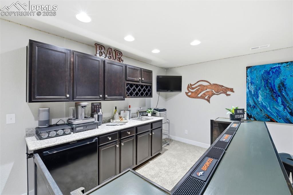 Image 32 of 50: Kitchen with dark wood finish cabinets, recessed lighting, and black fridge