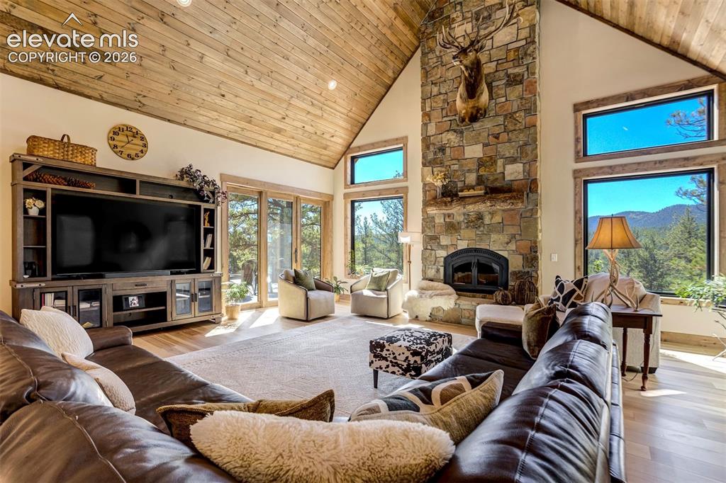 Image 11 of 50: Vaulted wood-finish ceilings, a stone fireplace, large windows with natural
