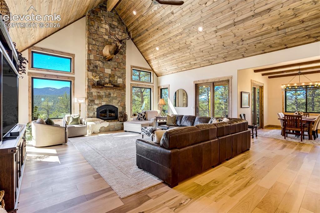 Image 17 of 50: Vaulted wood-paneled ceiling, stone fireplace with mantel, hardwood floorin