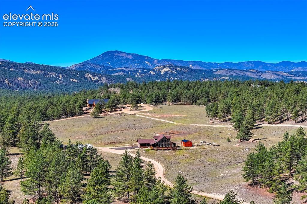 Image 37 of 50: Expansive property featuring mountainous terrain, mature evergreen trees, a
