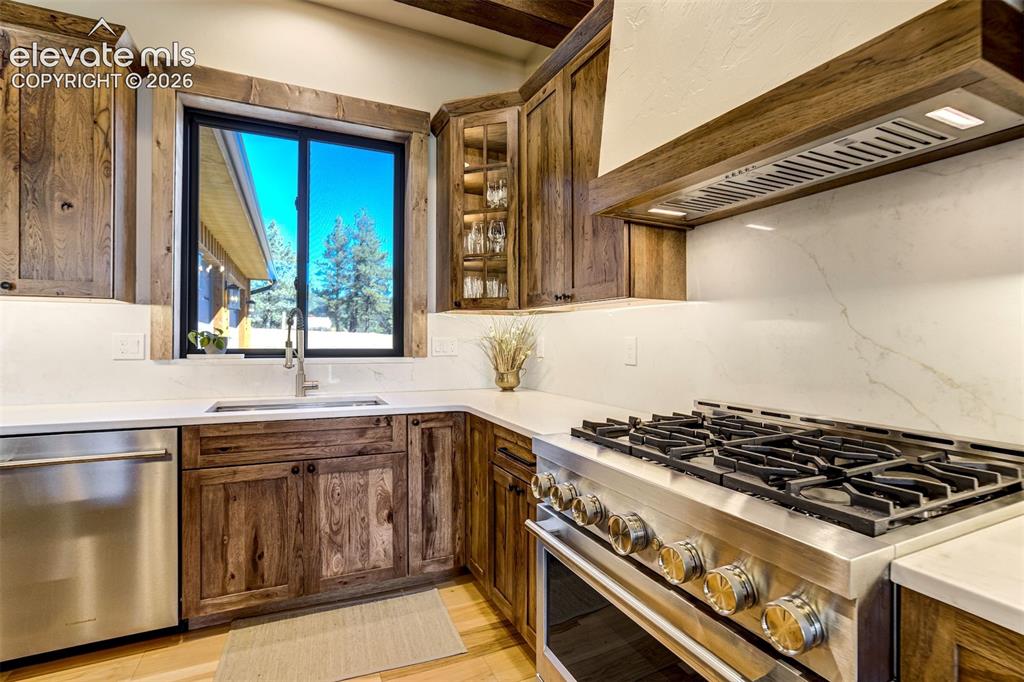 Image 7 of 50: Wood-finish cabinetry and trim, stainless steel appliances, white counterto