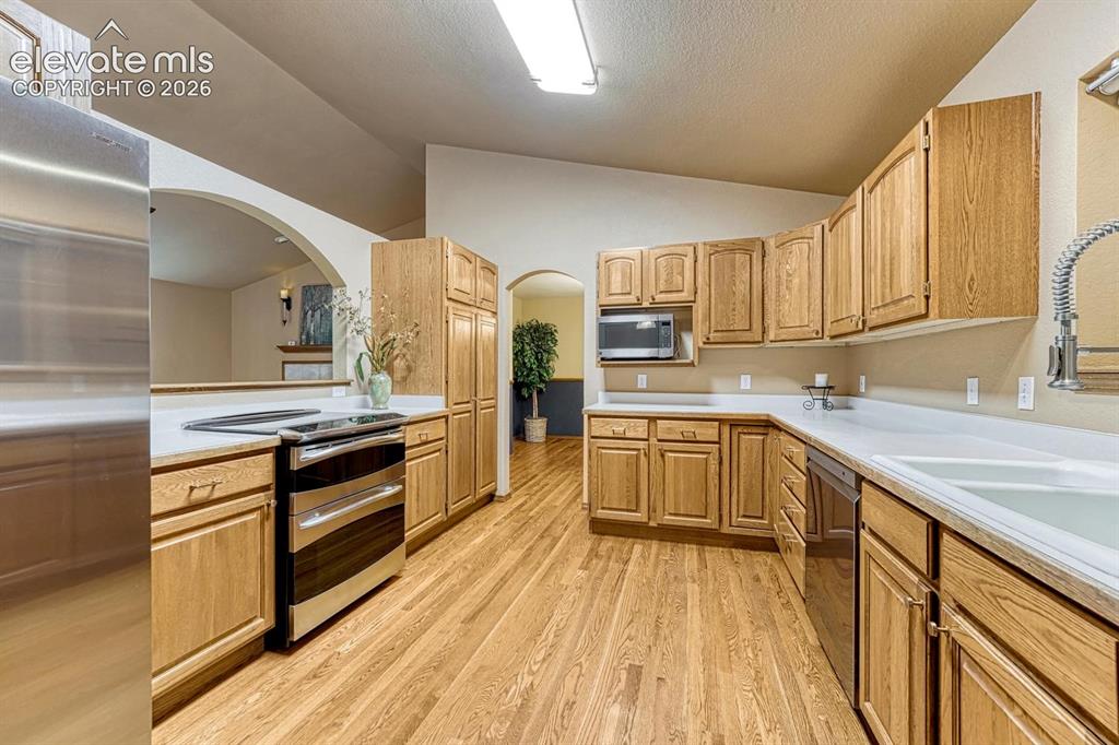Image 3 of 46: Kitchen with stainless steel appliances, solid surface counter and hardwood