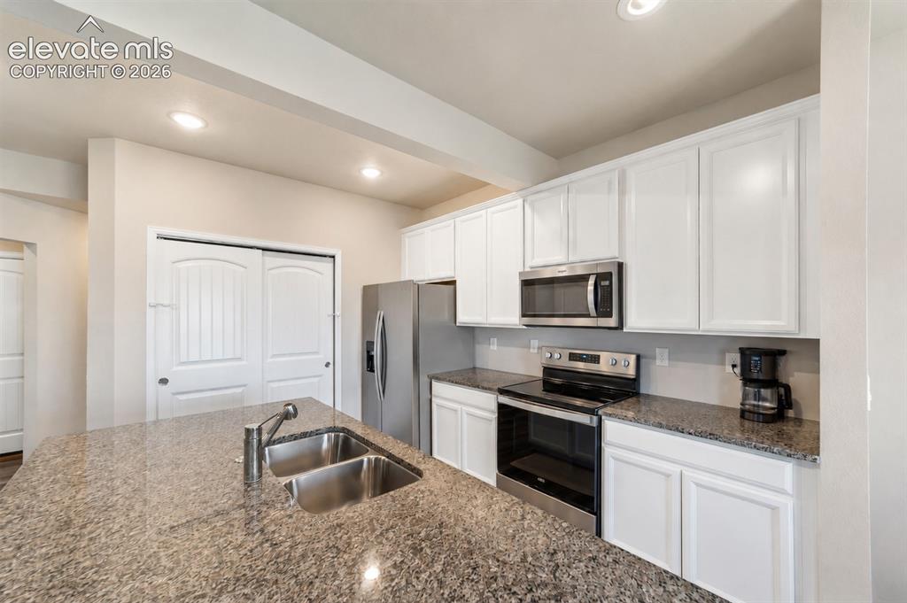 Image 4 of 21: Well-appointed kitchen featuring granite countertops, white cabinetry, and