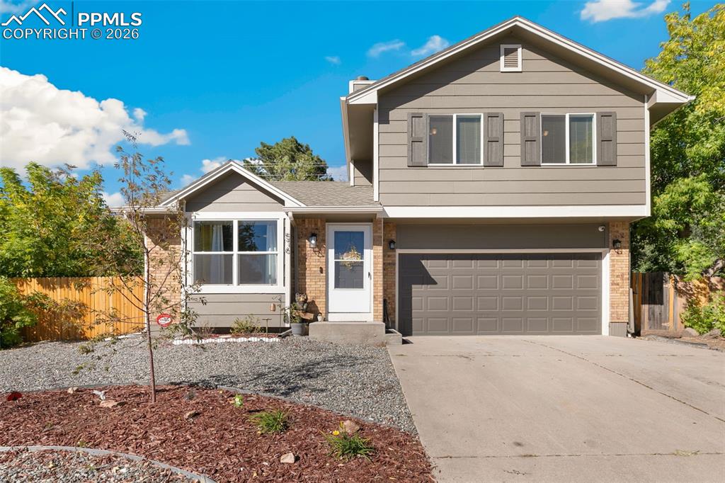 Caption: View of front of home featuring brick siding, concrete driveway, a garage, and roof with shingles