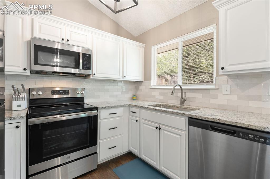 Image 19 of 28: Kitchen featuring appliances with stainless steel finishes, white cabinets,