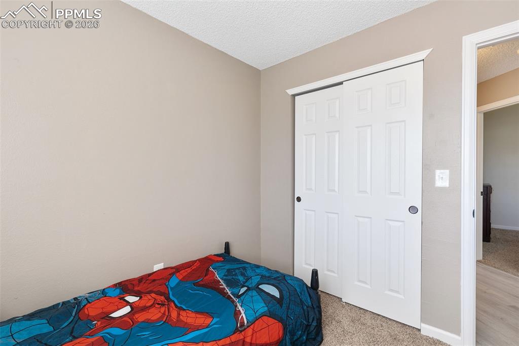 Image 6 of 28: Carpeted bedroom with a textured ceiling and a closet