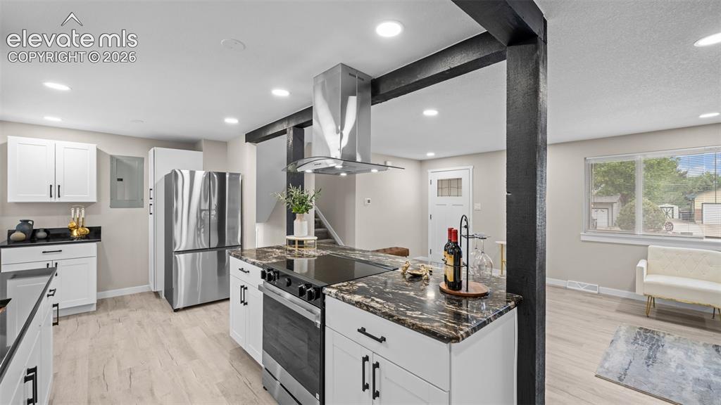 Image 11 of 45: Modern kitchen featuring an island with a built-in cooktop, stainless steel