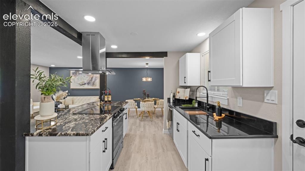 Image 12 of 45: Modern kitchen featuring white shaker cabinetry, dark granite countertops,