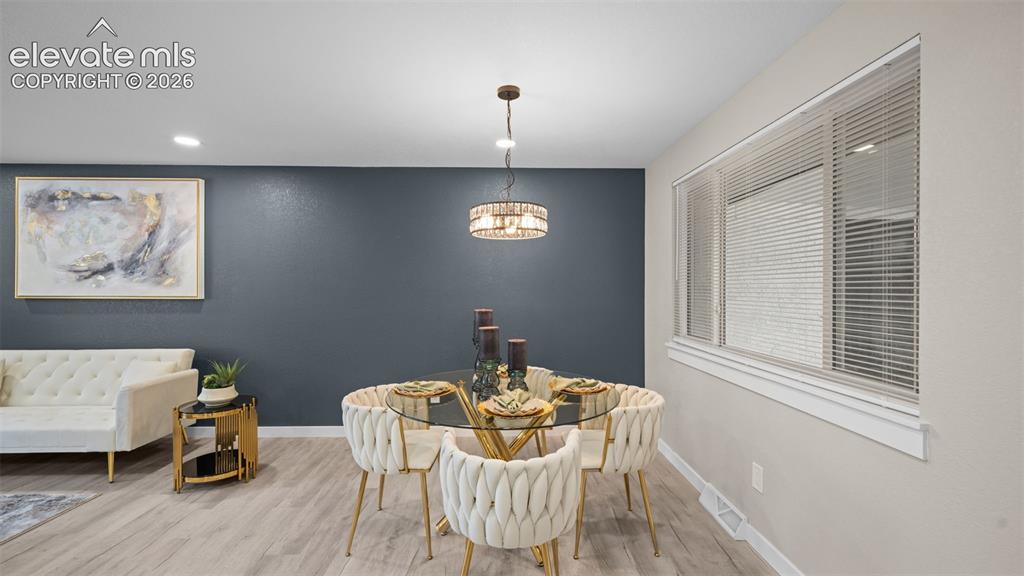 Image 15 of 45: Dining area featuring a contemporary pendant light fixture, light wood-fini