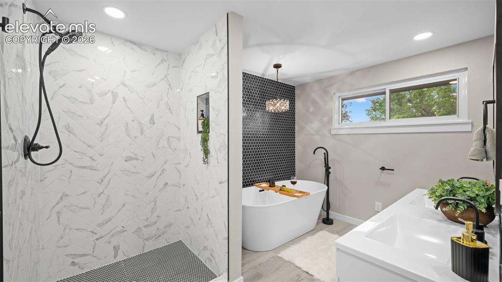 Image 19 of 45: Spacious bathroom featuring a freestanding soaking tub, a walk-in shower wi