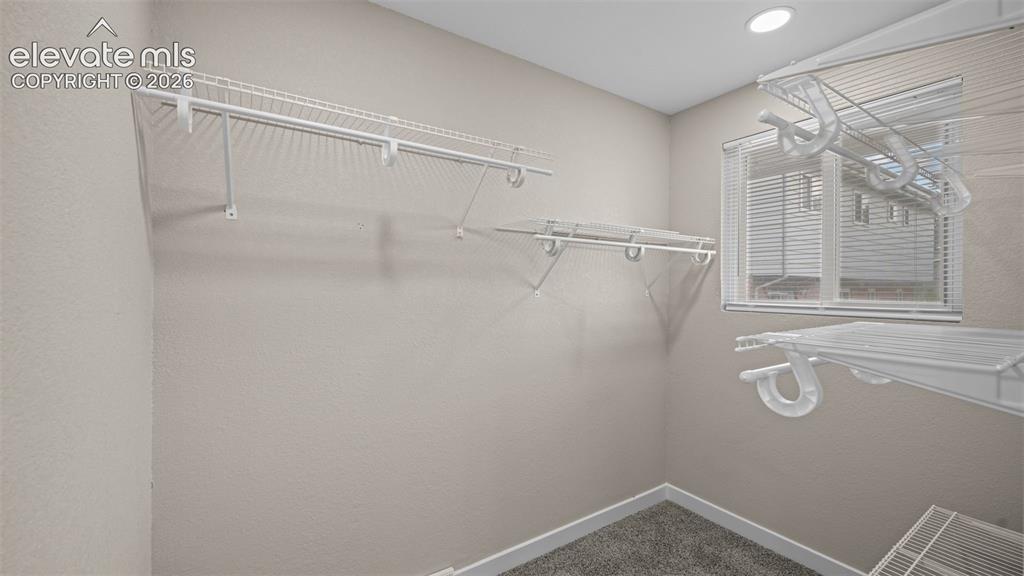Image 21 of 45: Walk-in closet featuring wire shelving, neutral-toned walls, gray carpeting