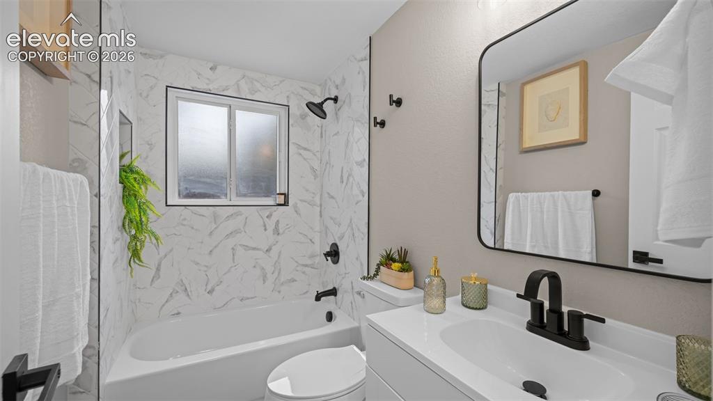 Image 22 of 45: Bathroom featuring a white bathtub with a tiled surround, a window with fro