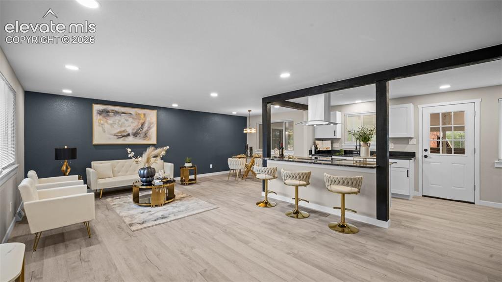 Image 5 of 45: Open-concept living space featuring wood-finish flooring, recessed lighting