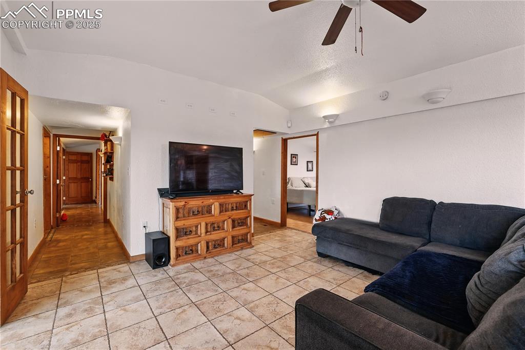 Image 21 of 50: Tiled living room featuring lofted ceiling and ceiling fan