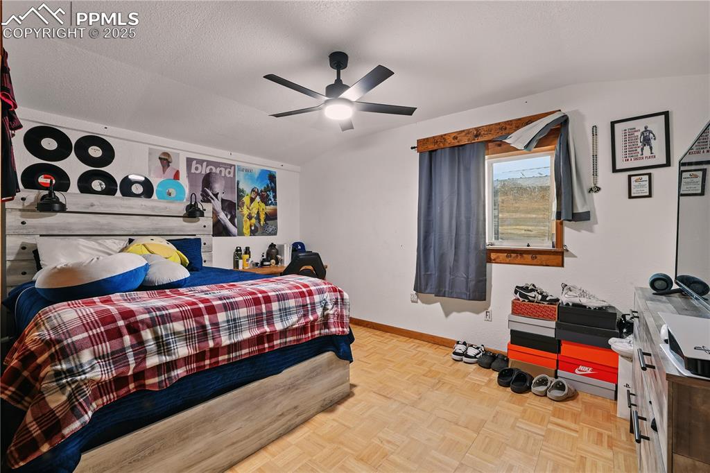 Image 30 of 50: Bedroom 3 with parquet wood floors and ceiling fan.