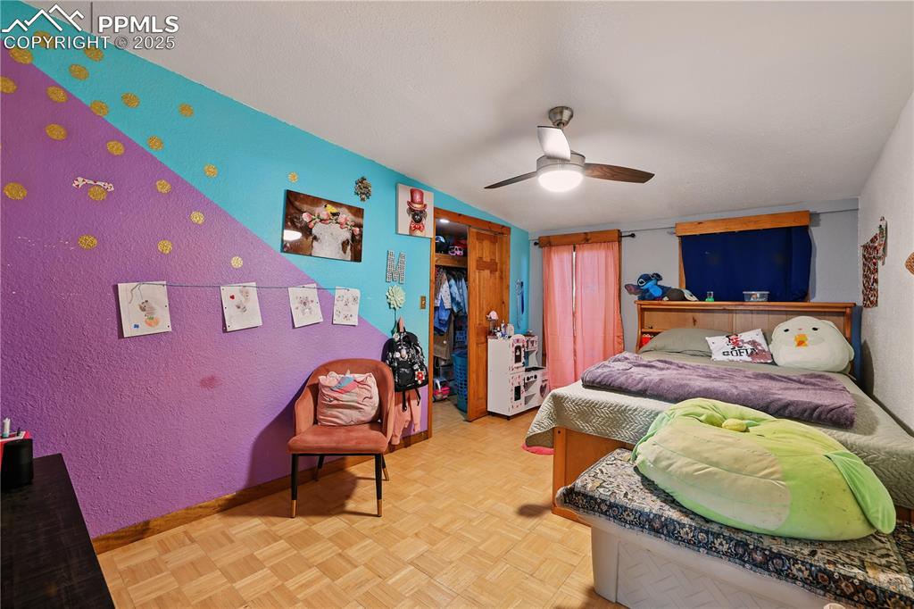 Image 35 of 50: Bedroom 4 with parquet wood floors and ceiling fan.