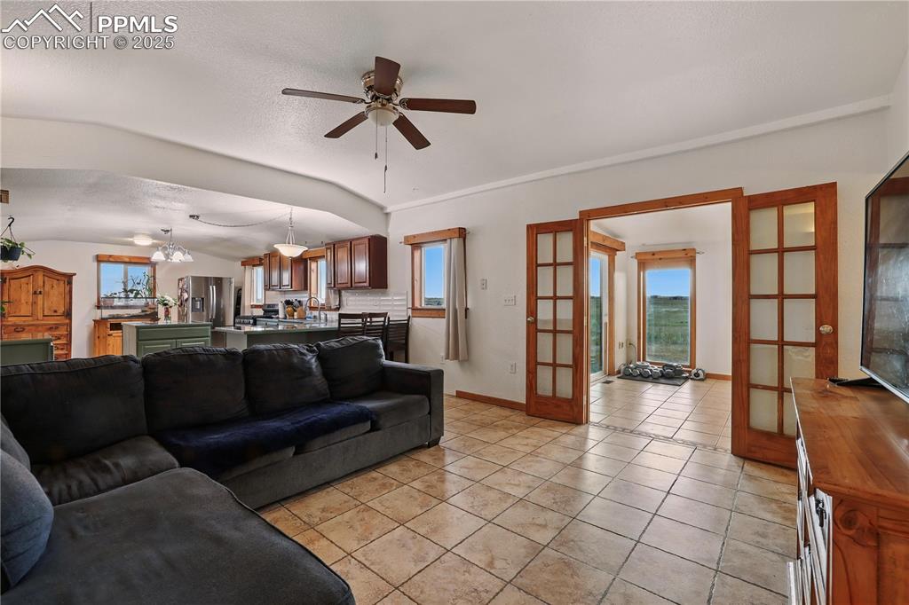 Image 4 of 50: Living room with tile flooring and french doors to the bonus room