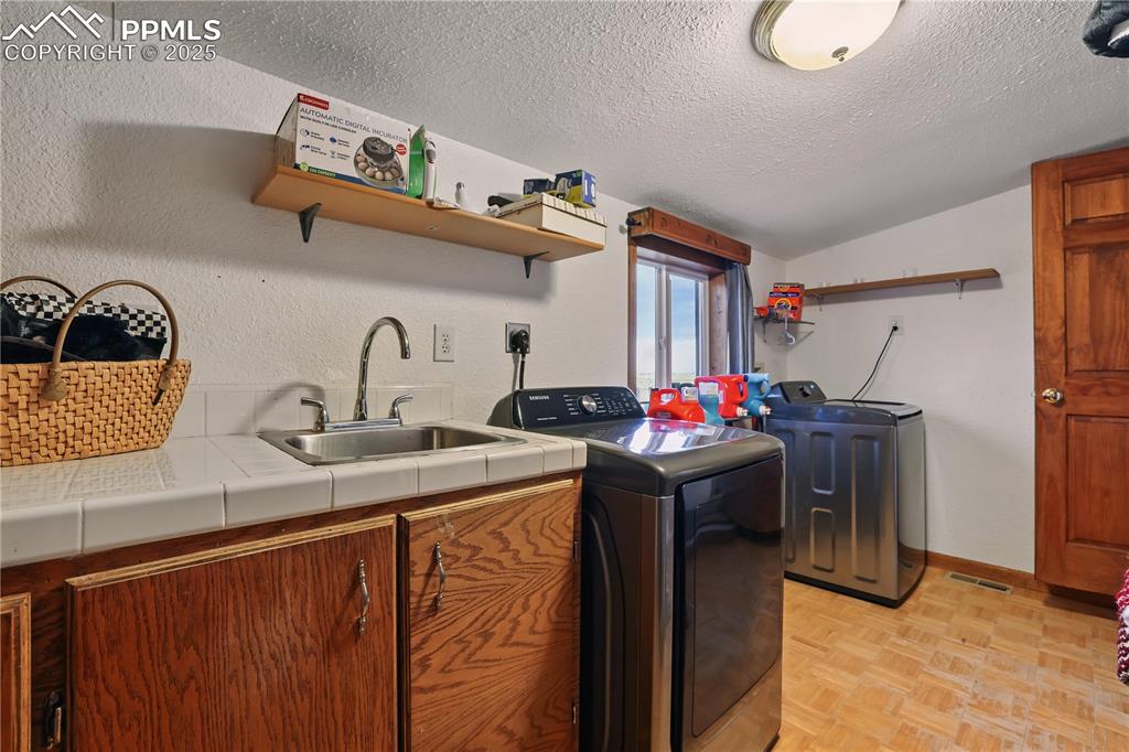 Image 40 of 50: Laundry room featuring a window, ample storage and laundry sink.