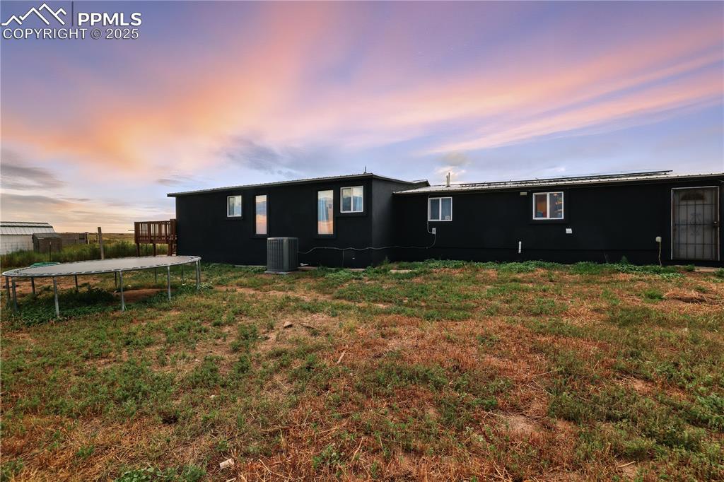 Image 42 of 50: Back of home at dusk featuring a trampoline and a fenced backyard