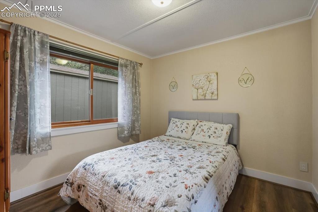 Image 18 of 47: The secondary bedroom has wood floors and an oversized window. 