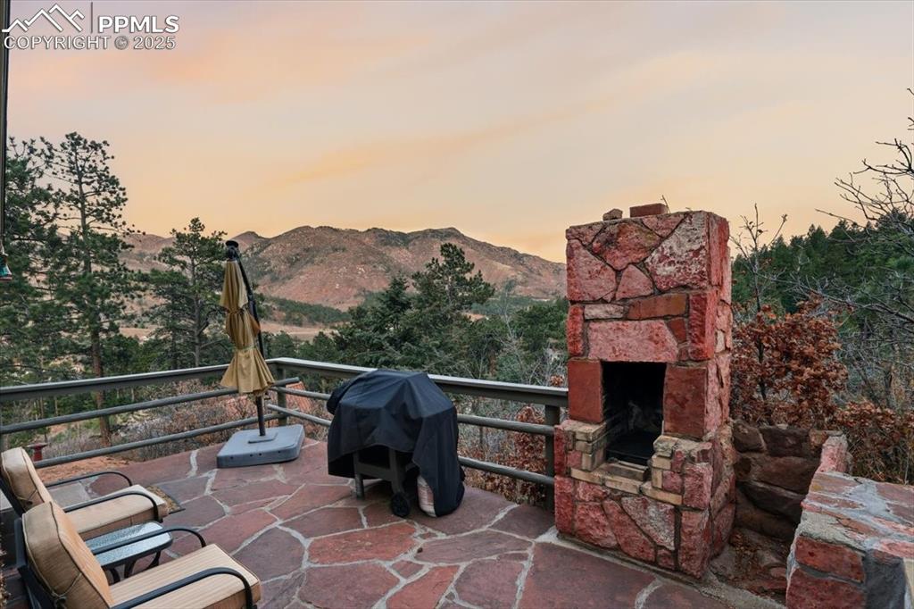 Image 27 of 47: The stone patio on the rear of the house features a wood-burning fireplace 