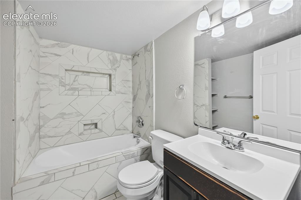 Image 26 of 34: Lower Level Full Bathroom with vanity, mirror, tiled tub/shower, and built 