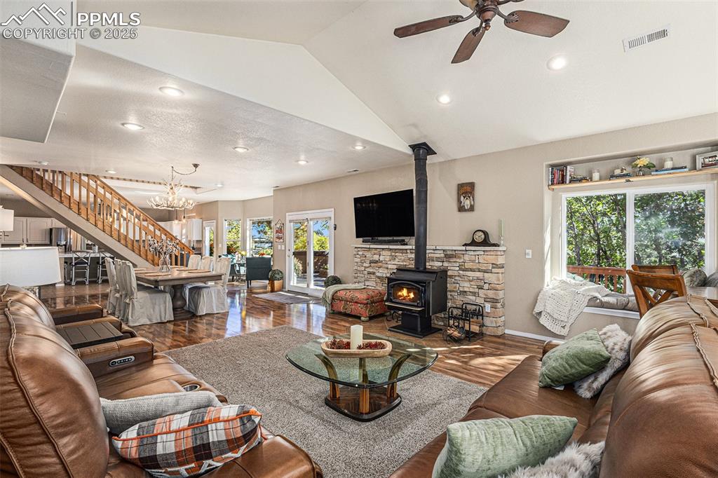 Image 10 of 47: Living room with a wood stove, wood finished floors, high vaulted ceiling, 