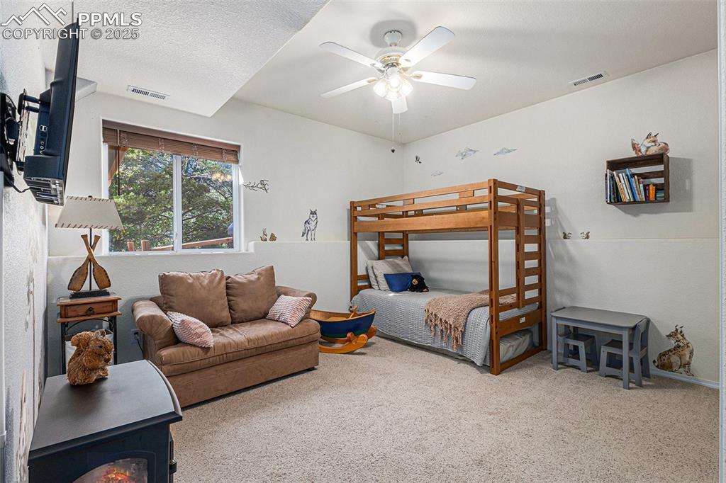 Image 31 of 47: Bedroom featuring a wood stove, light colored carpet, a closet, and a textu