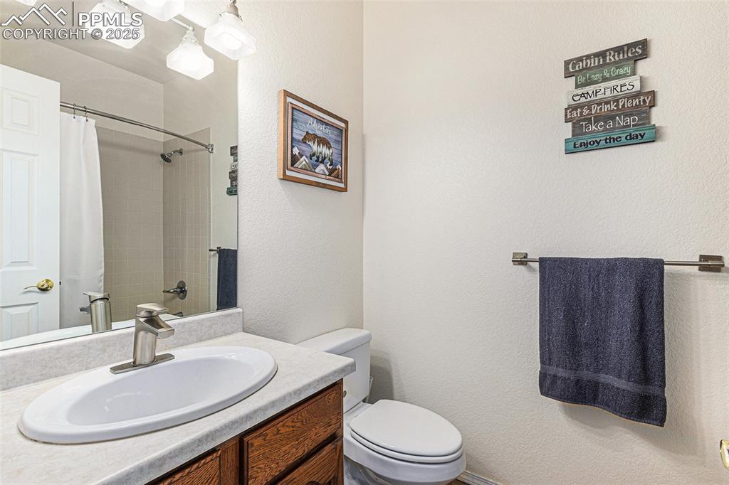 Image 33 of 47: Full bathroom with vanity, a textured wall, and a shower with curtain