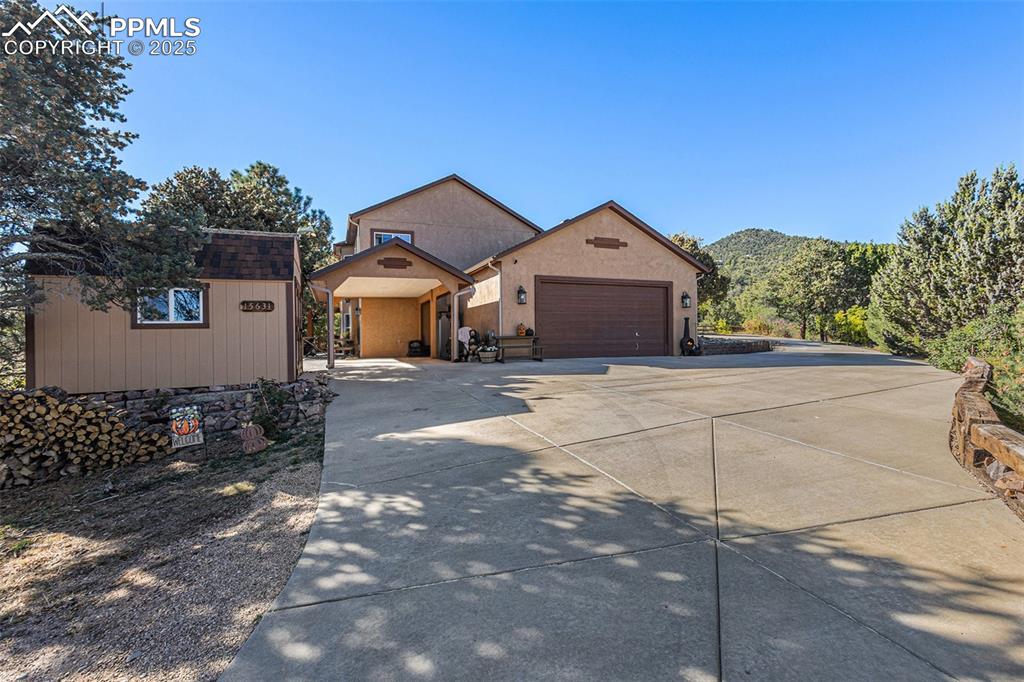 Image 38 of 47: View of front of property featuring driveway, stucco siding, an outbuilding