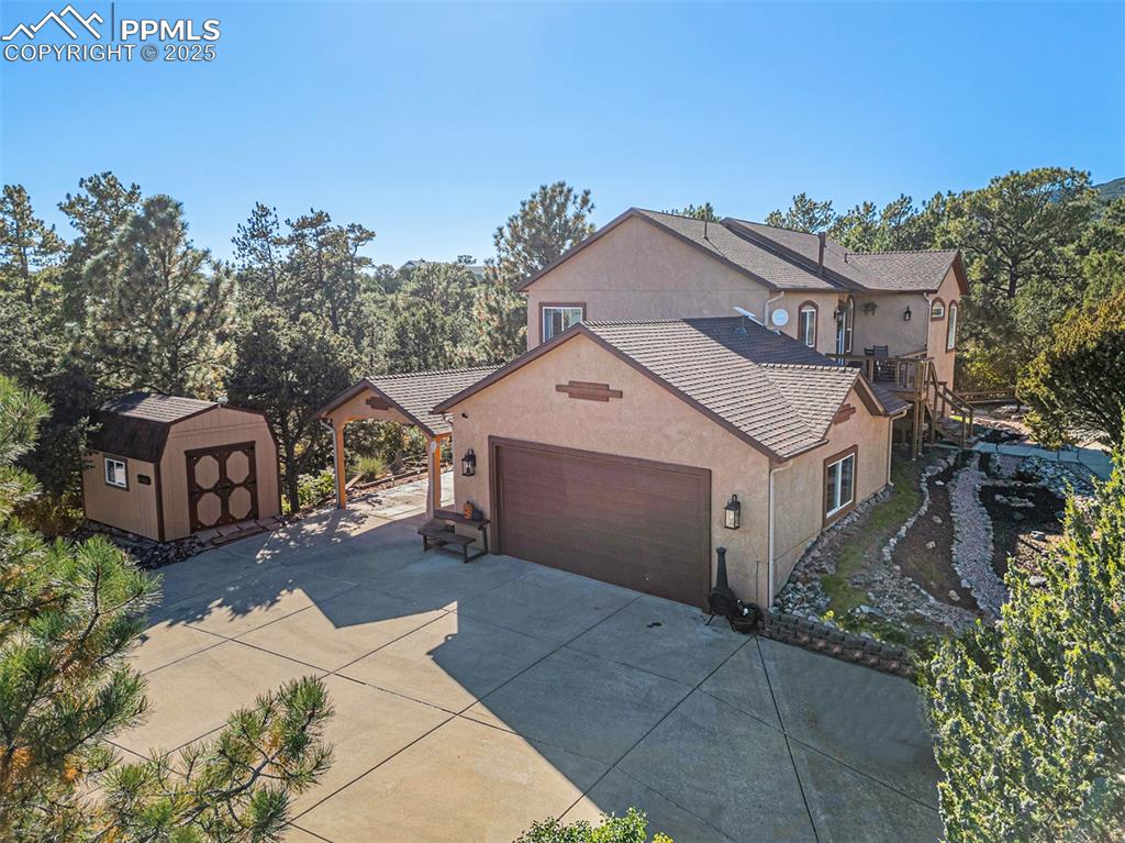 Image 39 of 47: View of property exterior featuring a storage unit, stucco siding, driveway