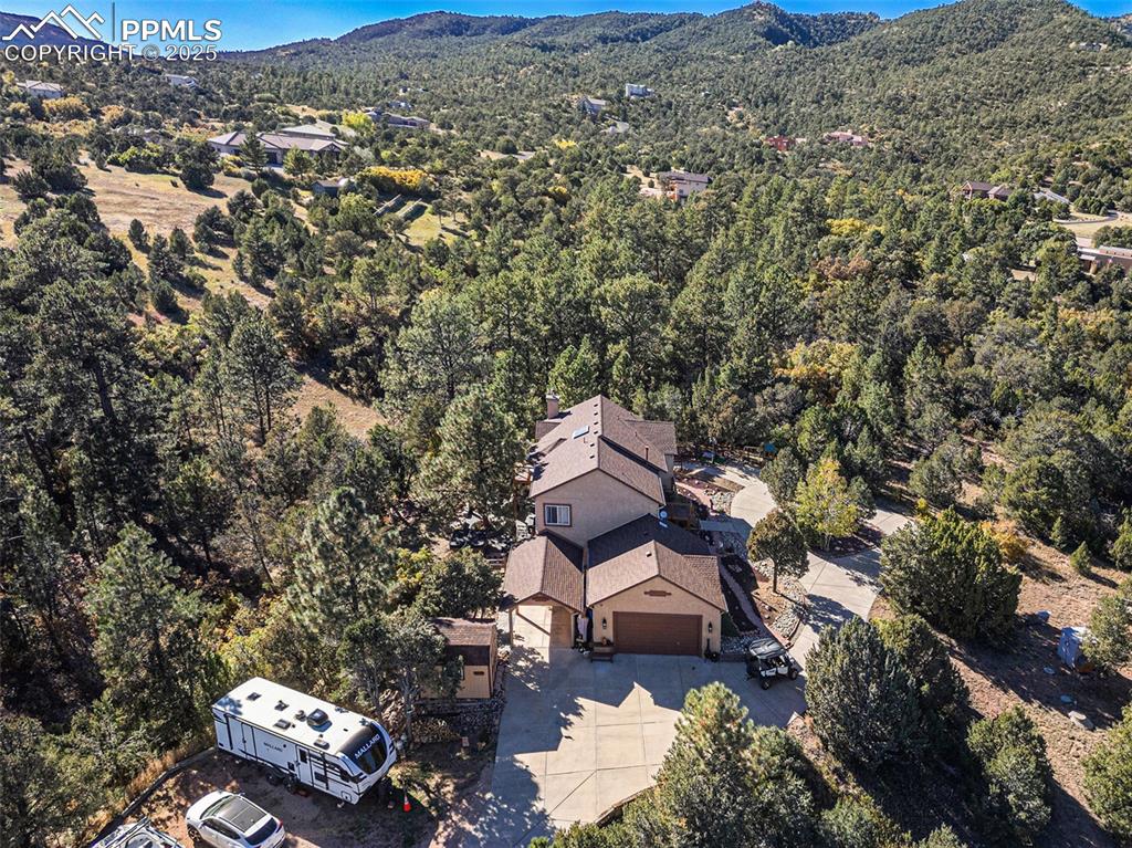 Image 44 of 47: View from above of property with a mountainous background and a forest