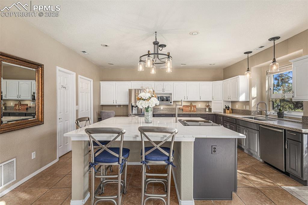 Image 7 of 47: Kitchen featuring hanging light fixtures, appliances with stainless steel f
