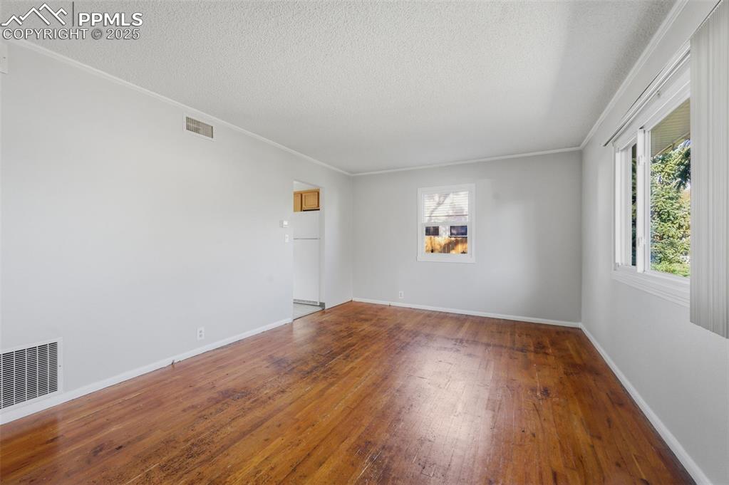 Image 18 of 50: Spare room featuring hardwood / wood-style floors, crown molding, healthy a