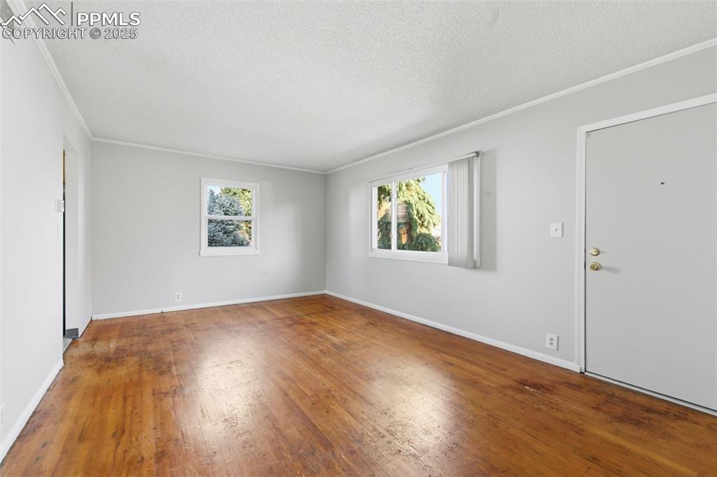Image 19 of 50: Spare room with crown molding, hardwood / wood-style flooring, and a textur
