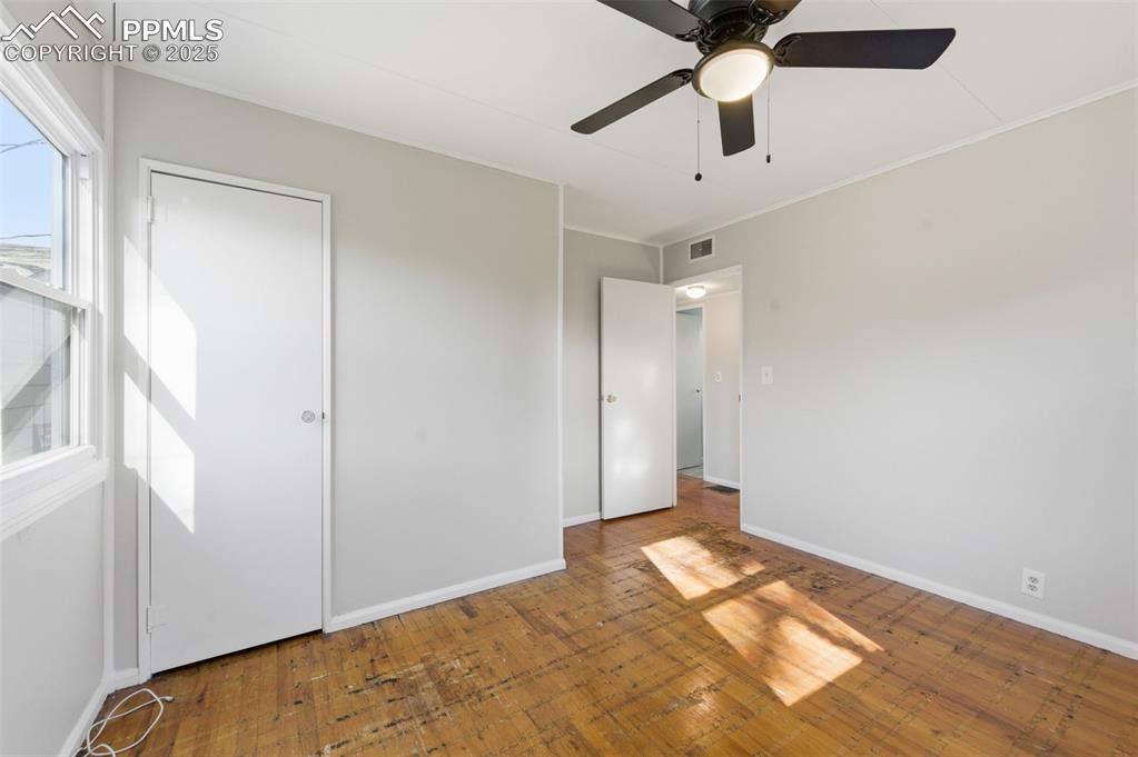 Image 35 of 50: Unfurnished bedroom with ornamental molding, ceiling fan, and wood-type flo