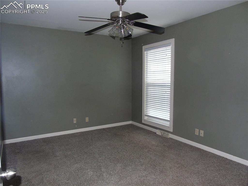 Image 22 of 29: Spare room with dark carpet and a ceiling fan