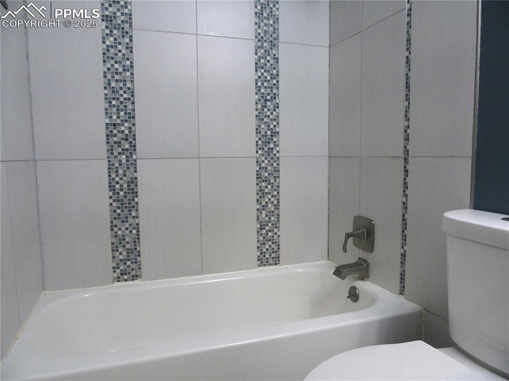 Image 26 of 29: Bathroom with toilet and bathtub / shower combination